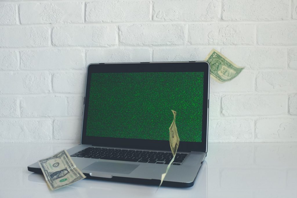 computer with three banknotes flying over